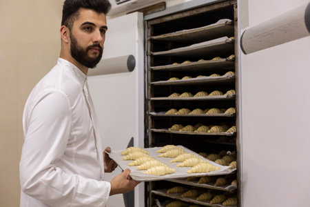 Closeup of pastry chef with tray of croissantの写真素材