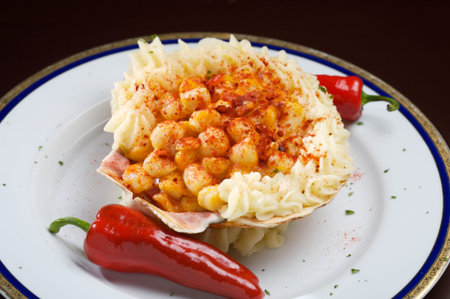 Plate of scallops served in a shell with red paprika powder.