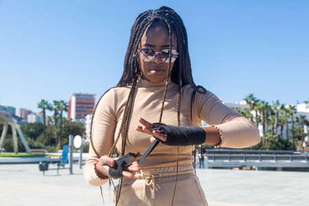 Portrait of beautiful young afro american woman putting bandages on her hands to practice martial arts, boxing.の写真素材