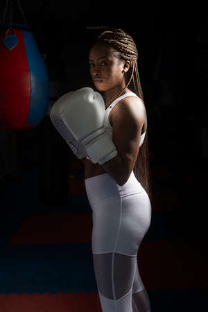 Portrait of Young afro american woman training boxing in gym with boxing gloves and white clothes.の写真素材