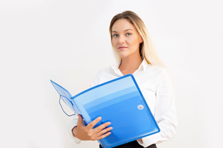 Beautiful young business woman looking at camera with blue folder in hands.