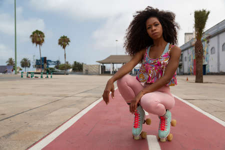 portrait of beautiful young afro woman on roller skates with urban backgroundの写真素材