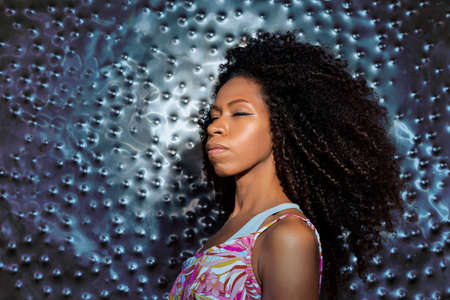 beautiful black woman with closed eyes on a metallic blue backgroundの写真素材