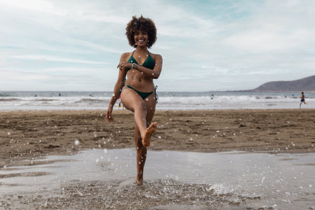 Beautiful African girl smiling playing with water with beach background.の写真素材