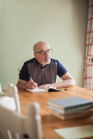 Elderly man relaxing at home, reading on an armchairの写真素材