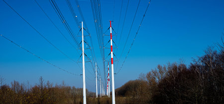 High voltage electric power lines attached to line towers within beautiful nature landscape with...