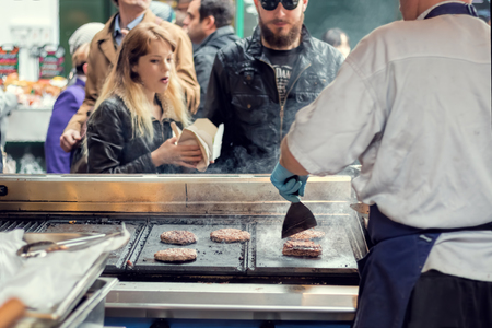 London, UK - June 2, 2016: Street food vendor grills burgers for customers, Bermondsey Market.のeditorial素材