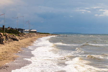 The Beach of Juelsminde in Denmark. View along the coastline and of the stormy Baltic Sea. Waves crash on the beach.の写真素材