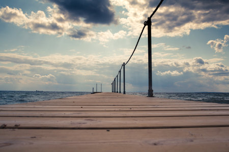 Wooden pier on the seashore. Blue sky with clouds. On the Baltic Sea coast of Denmark.の写真素材
