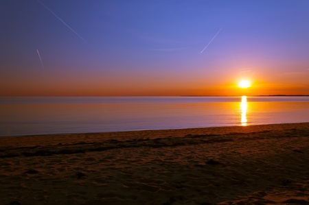 sunset over the ocean with visible streaks in the skyの写真素材