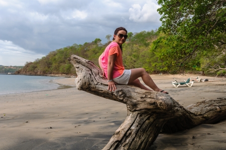 happy woman sitting on a stump thrown by the wavesの写真素材