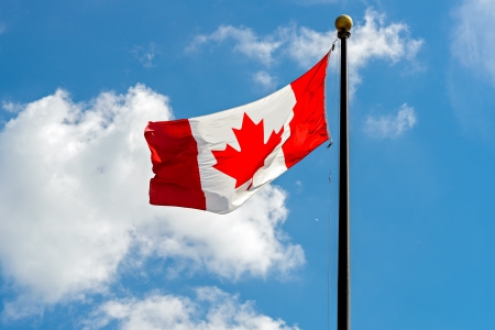 Canadian Flag in front of vivid, sunny, cloudy skyの写真素材