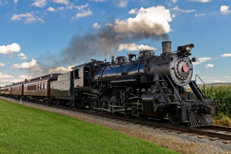 historic steam train passes through the fieldsの写真素材