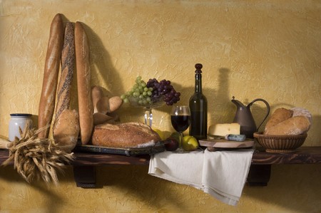 Bread, cheese, wine and grapes against a tuscan plaster wallの写真素材