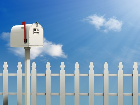 A Mail Box against a Blue Sky and white picket fence backgroundの写真素材