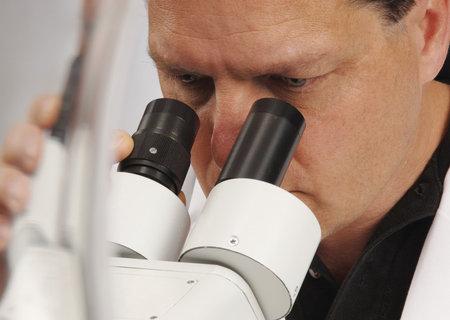 Closeup of a man looking into a microscope