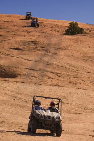 3 side-by-side ATVs coming down the side of a rock decline. 