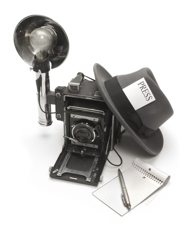 Retro photo journalist camera, fedora hat with a press pass in the headband, and ballpoint pen with notepadの写真素材