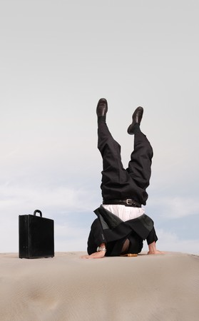 Businessman standing on his head with his head in the sandの写真素材