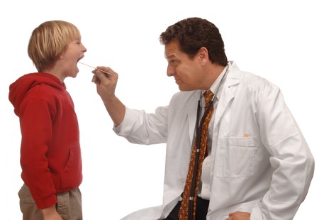 Doctor looking at a young boy's throat with a tongue depressorの写真素材