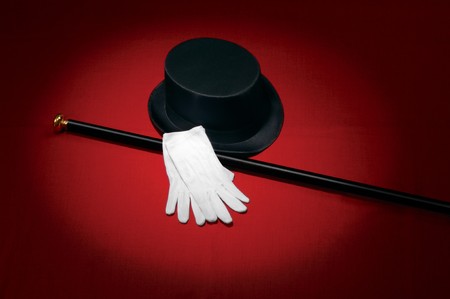 Top hat, white gloves and black cane on red background under a spotlightの写真素材