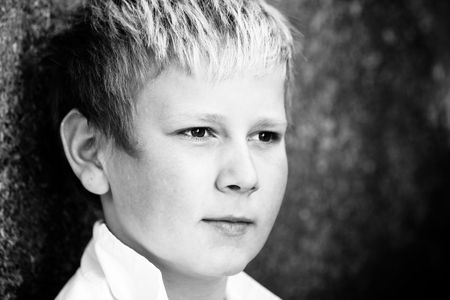 Young boy leaning against concrete wall outdoorsの写真素材