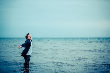 Thoughtful Teen Boy in Semi Formal Attire, Standing at the Sea with Copy Space in Monochrome Colorの写真素材