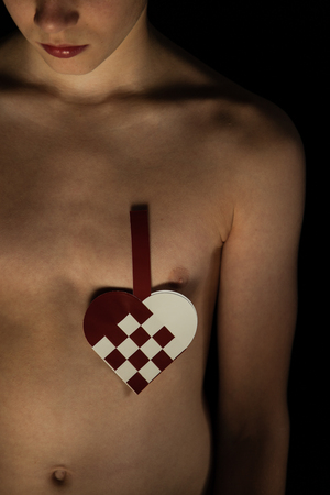 Experimental image of shirtless boy in the dark with checkered heart on his chestの写真素材