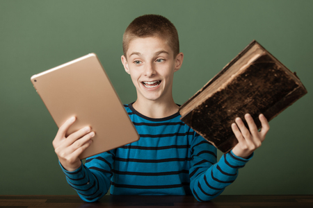Single excited boy in blue striped shirt comparing two different books. One older and the other newer.の写真素材