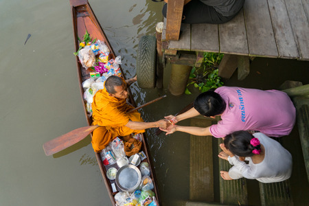 Amphawa, Thailand. October 25, 2015. Monk receiving morning Alms in Amphawa from a worshiper.のeditorial素材
