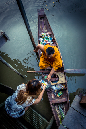 Amphawa, Thailand. October 25, 2015. Monk receiving morning Alms in Amphawa from a worshiper.のeditorial素材