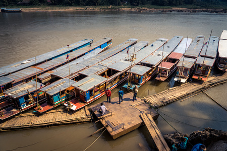 Boats lined up at dock on a river in Luang Prabang, Loasのeditorial素材