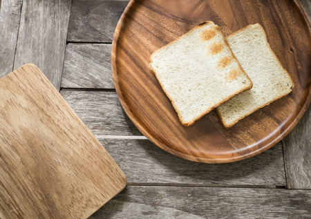 Toast bread on wooden plate and wooden breadboard on wood backgroundの写真素材