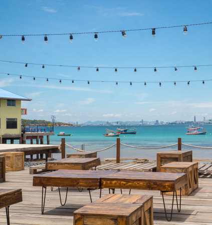 Wooden table and box at outdoor restaurant. Background is landscape of boat in the sea and Pattaya city.Shooting from Koh Lan Island. Chonburi, Thailandの写真素材
