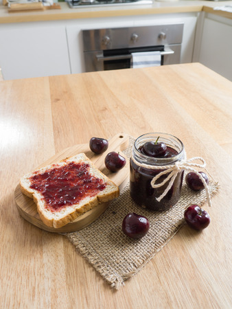 Glass with homemade Cherry jam and toast on wooden backgroundの写真素材