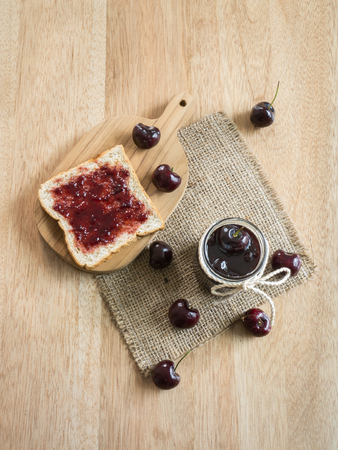 Glass with homemade Cherry jam and toast on wooden backgroundの写真素材