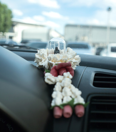 Small buddha amulet with garland on the car console. ( Believability of Thailand and Buddhism. Small buddha amulet is sacredness to save from danger)の写真素材