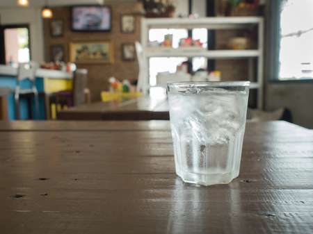 Glass of cool  water with ice on wood table in the  restaurantの写真素材