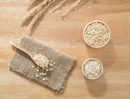Top view -  Wheat flakes in wooden bowl on wooden background - Raw food ingredients