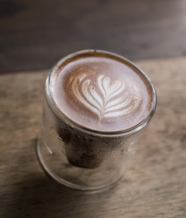 A glass of latte art coffee on wooden backgroundの写真素材