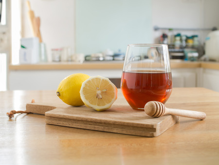 Honey lemon - lemon on chopping board and Glass of honey and honey dipper on wooden tableの写真素材