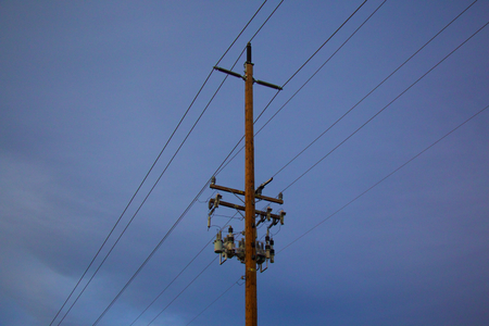Pole and Power lines with blue background and cloudsの写真素材