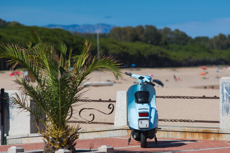 blue vintage scooter stands by a palm at the beach. Post process in vintage styl.の写真素材