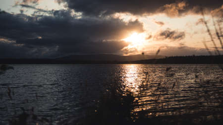 Sunset behind the mountains in font of a bay. Sun setting at the Scottish coast.の写真素材