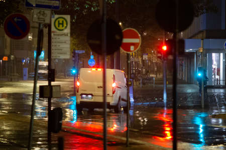 Rainy night in the big city, cars driving on street. Defocused image. traffic lights and many street signs in the foreground. car, transporter .の写真素材