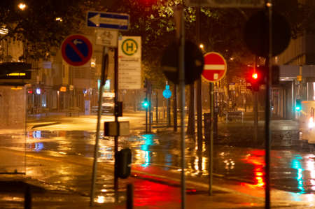 Rainy night in the big city, cars driving on street. Defocused image. traffic lights and many street signs in the foreground.の写真素材
