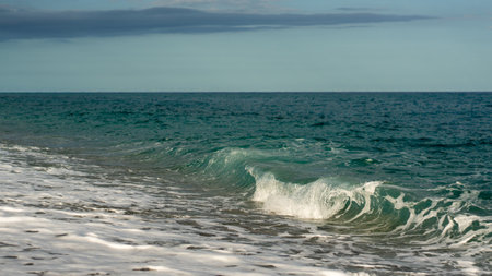 small wave crashing at a beach in crystal clear waterの写真素材