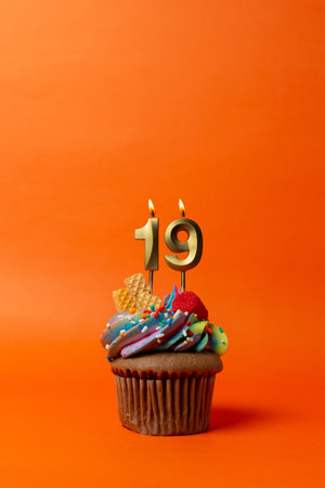 cupcake on orange background with birthday candles - birthday cake with numberの写真素材