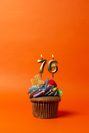 birthday cake with number 76 - cupcake on orange background with birthday candlesの写真素材