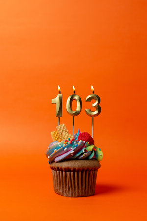 birthday cake with number 103 - cupcake on orange background with birthday candlesの写真素材